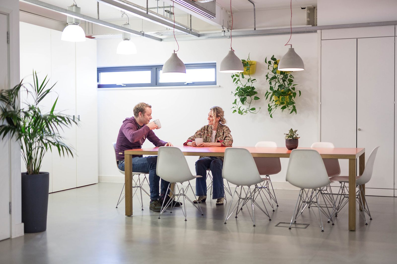 Two members chatting over coffee at the long table in the third-floor kitchen